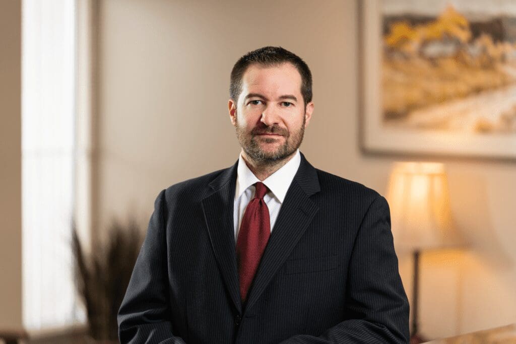 Professional headshot of man in suit, red tie
